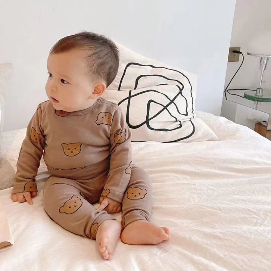 Bébé assis portant un pyjama marron avec adorables motifs ours