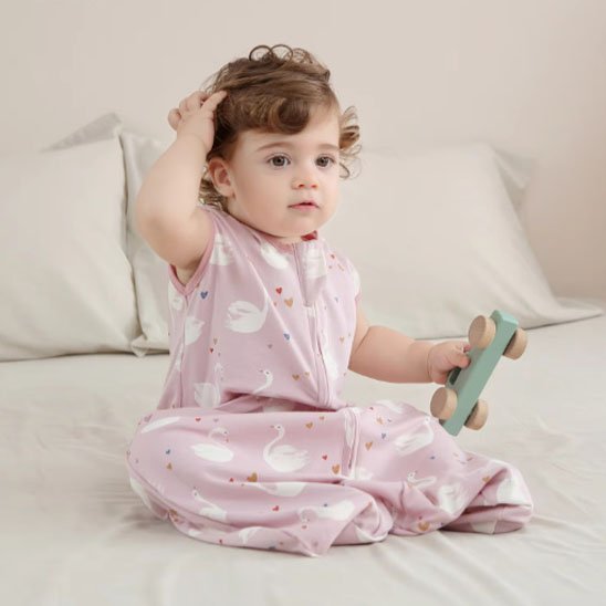 Bébé dans gigoteuse rose motifs cygnes et étoiles