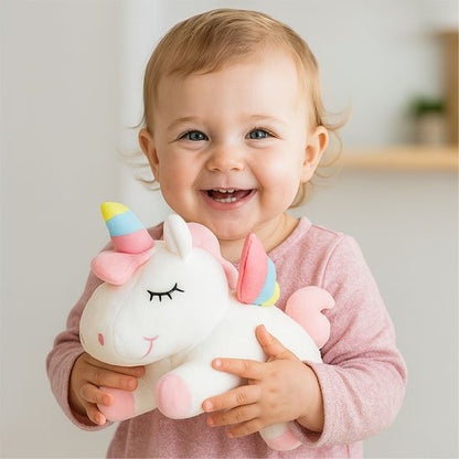 Bébé joyeux tenant peluche licorne blanche douce avec crinière arc-en-ciel