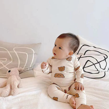 Bébé mignon assis en pyjama beige motif ours avec peluche