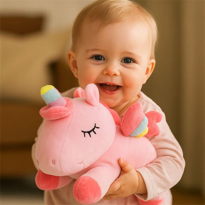 Bébé souriant câlinant  peluche licorne rose douce et colorée