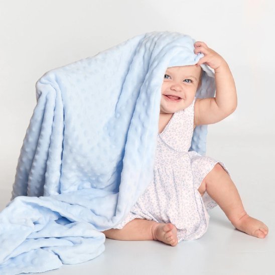 Bébé souriant jouant à cache-cache avec couverture bebe bleue minky douce