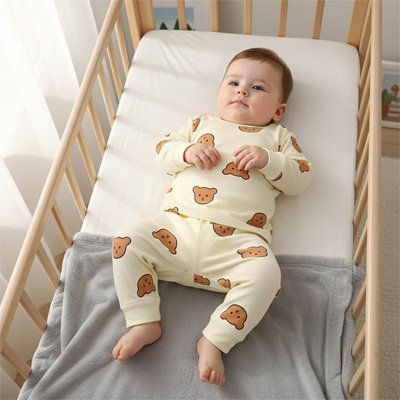 bébé dormant paisiblement en pyjama beige motif ours dans lit