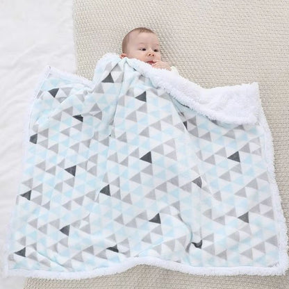 Bébé en vêtements blancs allongé sur couverture géométrique triangulaire bleu et gris, démonstration de la taille et du confort