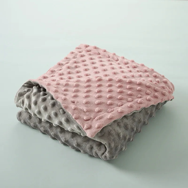couverture  bébé réversible pliée présentant  couleurs rose et gris avec texture gaufrée distinctive, illustrant options de coloris disponibles