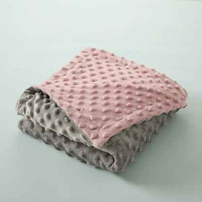 couverture  bébé réversible pliée présentant  couleurs rose et gris avec texture gaufrée distinctive, illustrant options de coloris disponibles
