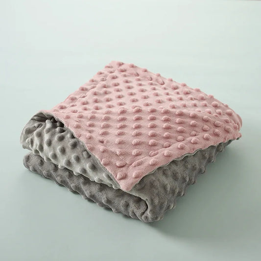 couverture  bébé réversible pliée présentant  couleurs rose et gris avec texture gaufrée distinctive, illustrant options de coloris disponibles