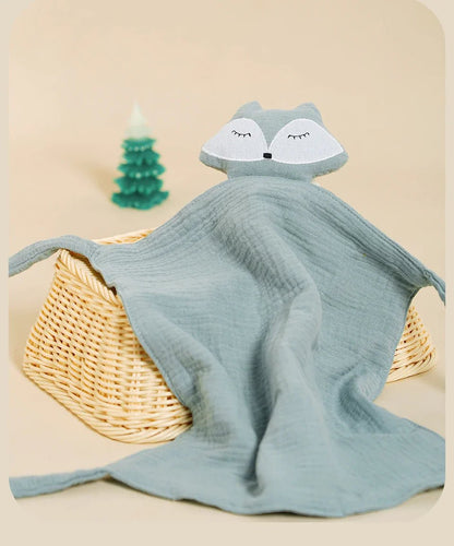 Doudou Renard bleu clair en mousseline sur  panier, avec  petit sapin en arrière-plan