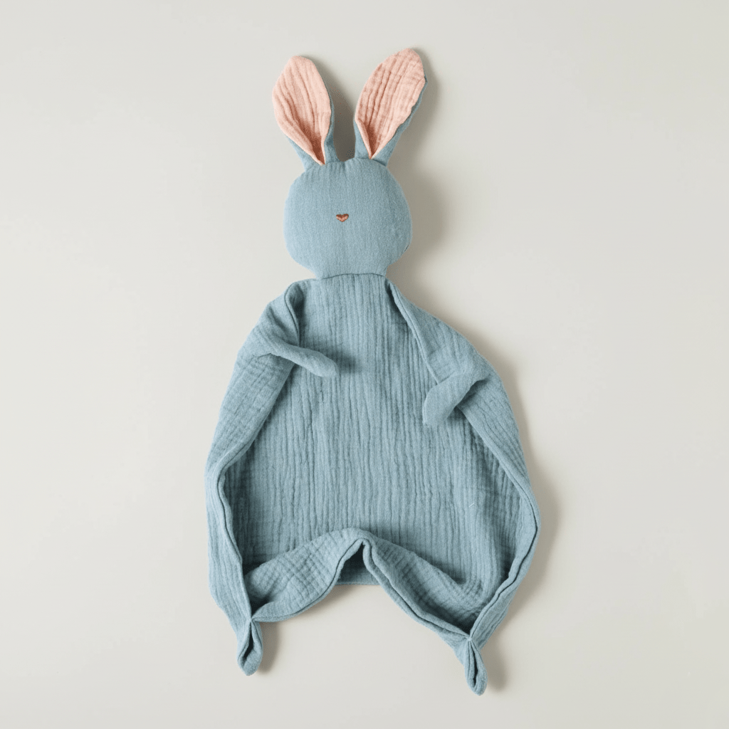 Doudou Lapin bleu pastel en mousseline, oreilles roses, sur fond clair